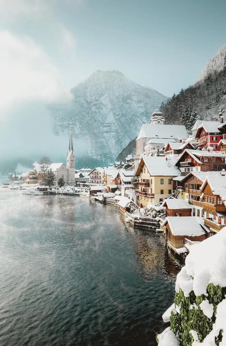 Ufer des Hallstätter Sees im Winter mit kunstvollen Hausfassaden und Berglandschaft im Hintergrund