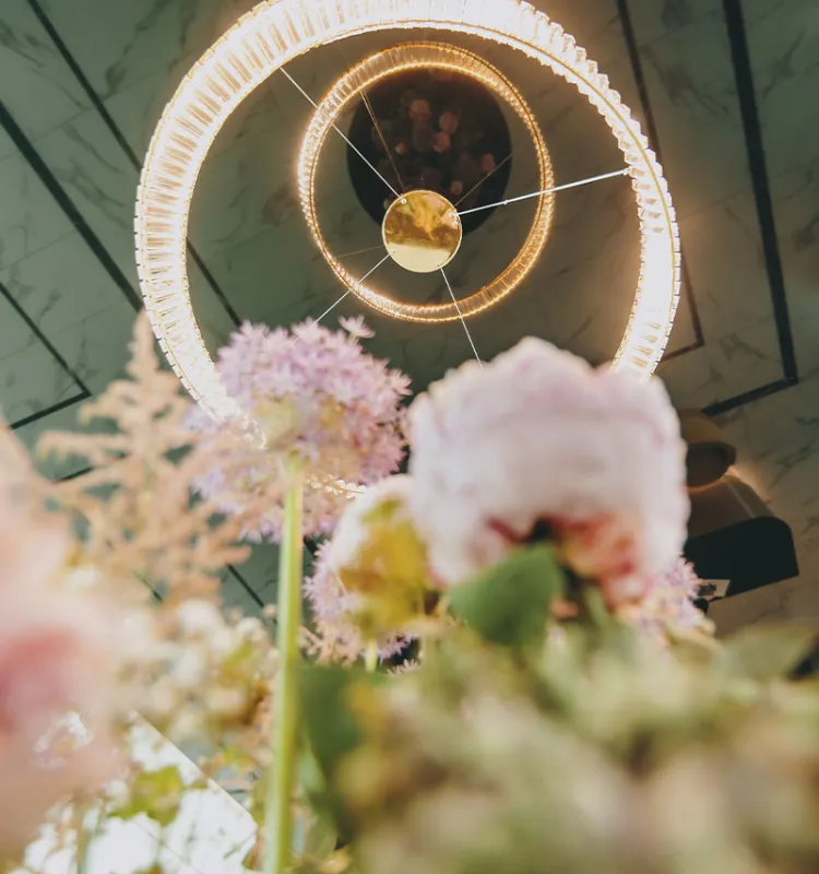 Porträt vom Deckenleuchter im Grand Elisabeth Hotel mit zahlreichen Urlaubsangeboten, von floraler Dekoration im Vordergrund umrahmt