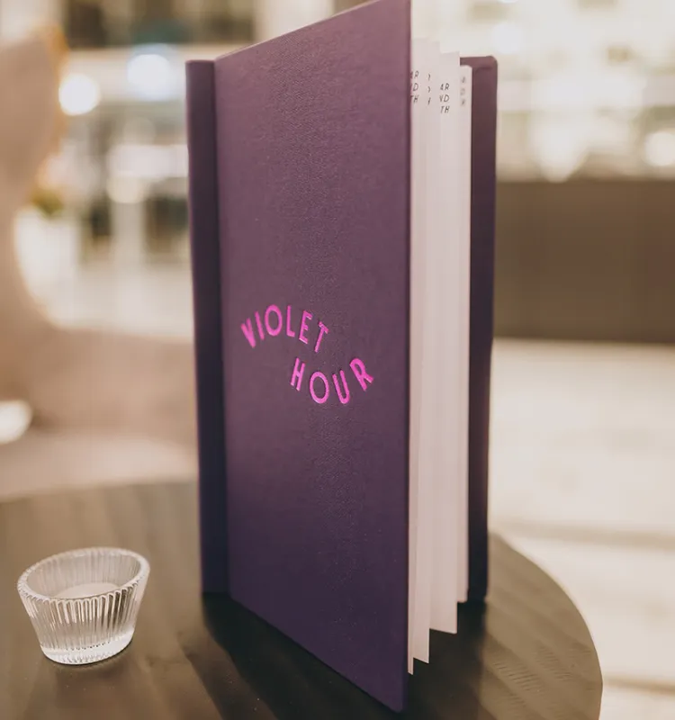 Die stilvolle Cocktailkarte der Hotelbar Violet Hour mit geprägtem Logo in Pink