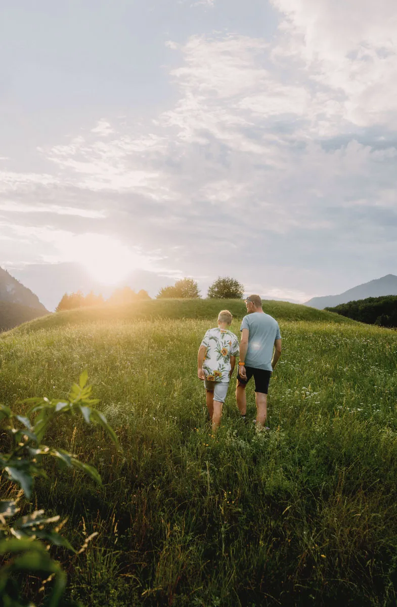 Zwei Personen spazieren durch eine sommerlich grün bewachsene Wiese im Kurort Bad Ischl