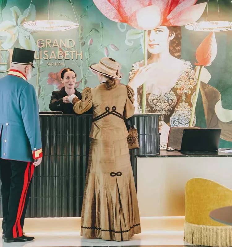 Porträt von Gästen in historischer Kleidung an der Rezeption im Grand Elisabeth Hotel in Bad Ischl.