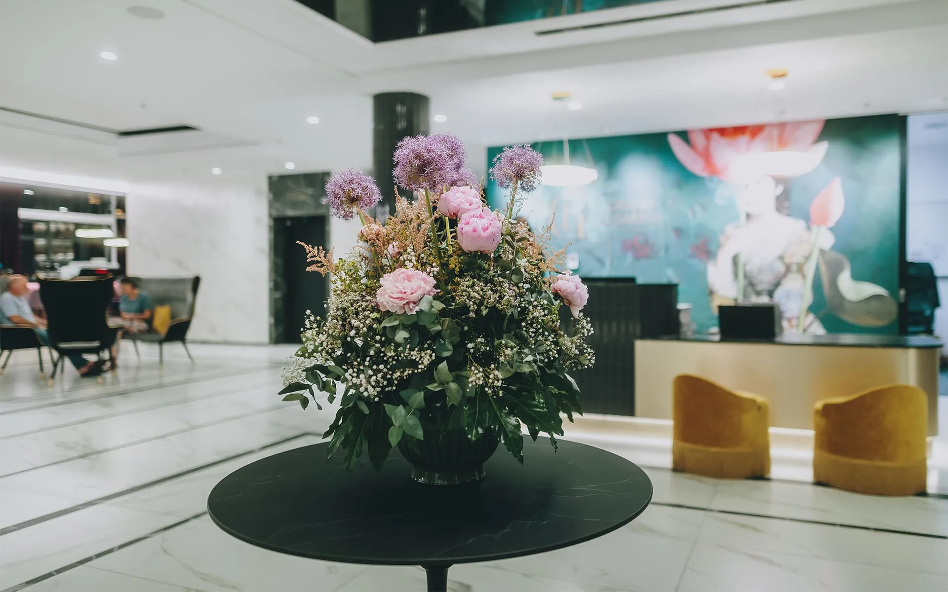 Im Foyer des Grand Elisabeth Hotels steht mittig ein runder schwarzer Tisch mit einer Vase voller Blumenpracht