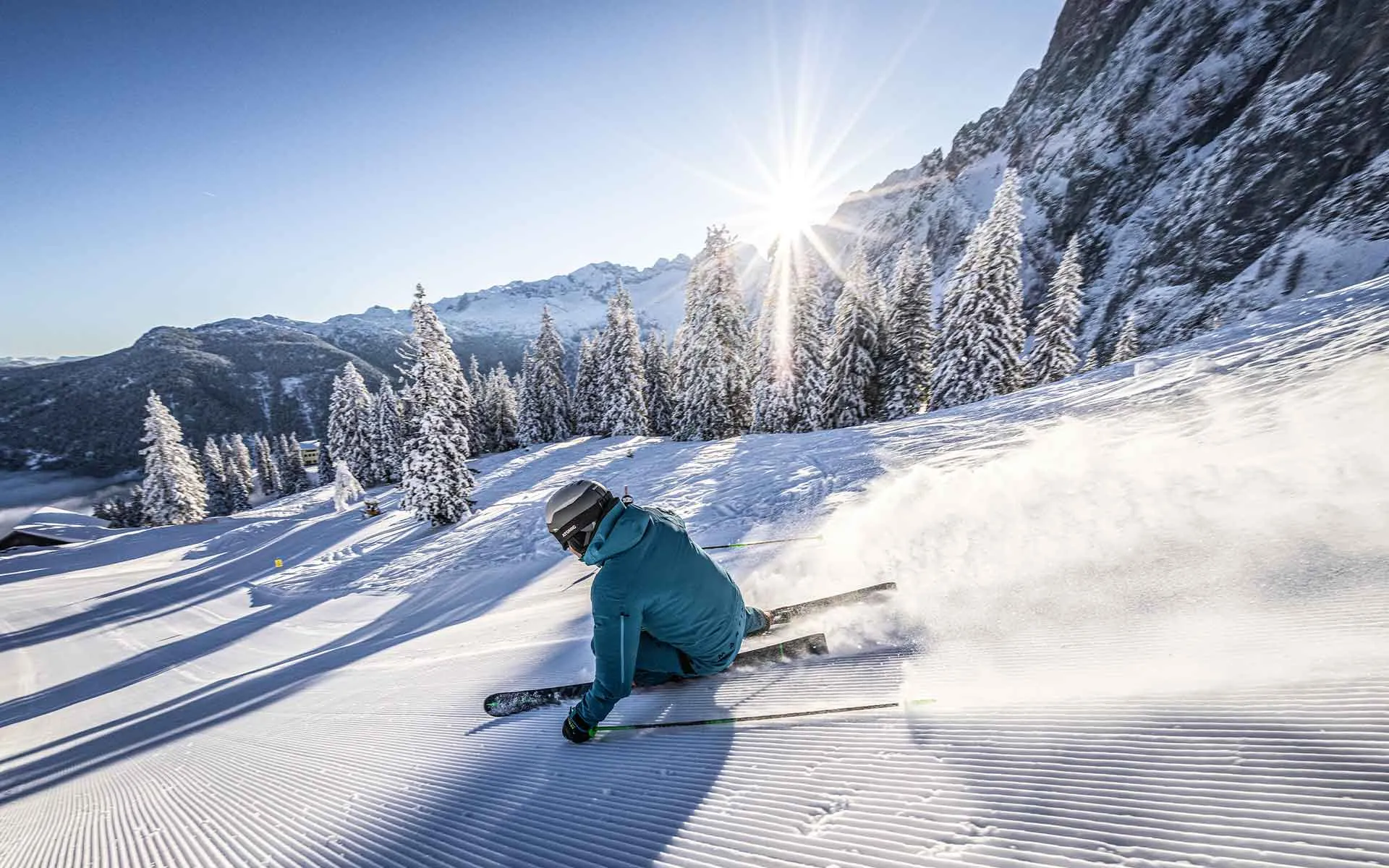 Eine Person fährt auf Skiern im Salzkammergut eine Piste hinab, im Hintergrund erheben sich majestätisch die Berge