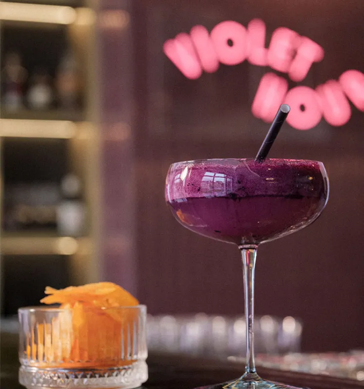 Fruchtiger Cocktail im Wellnesshotel Grand Elisabeth vor violettem Barhintergrund mit Neonschrift