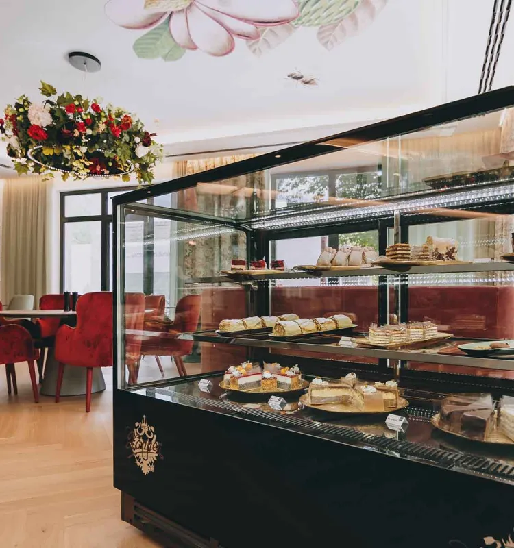 Porträt einer reich gefüllten Kuchenvitrine mit Blick auf das Grand Liberté im Grand Elisabeth Hotel Bad Ischl.