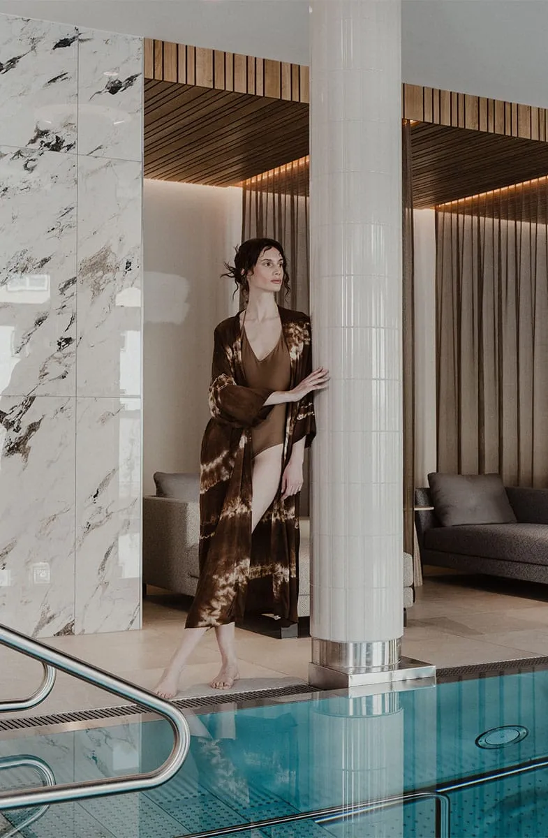 Frau im Bademantel am Pool im Wellnessbereich des Grand Elisabeth Hotels.
