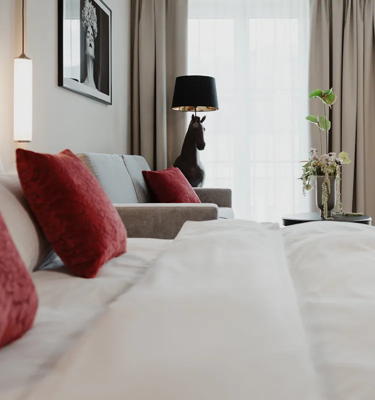 Edles Deluxe Doppelzimmer im Grand Elisabeth in  Bad Ischl mit Samtbett, Couch, Blumenarrangement und Kunstwerken.