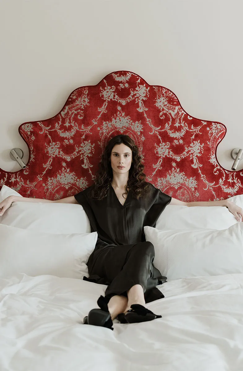 Frau sitzt entspannt im Bett eines Zimmers im Grand Elisabeth Hotel