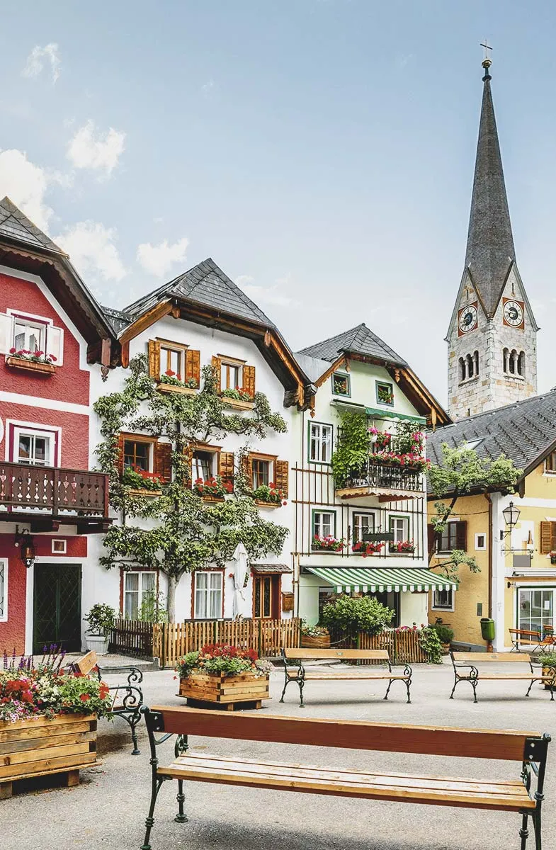 Kunstvoll verzierte Hausfassaden in Hallstatt mit Holzläden und Begrünung, davor ein malerischer Marktplatz