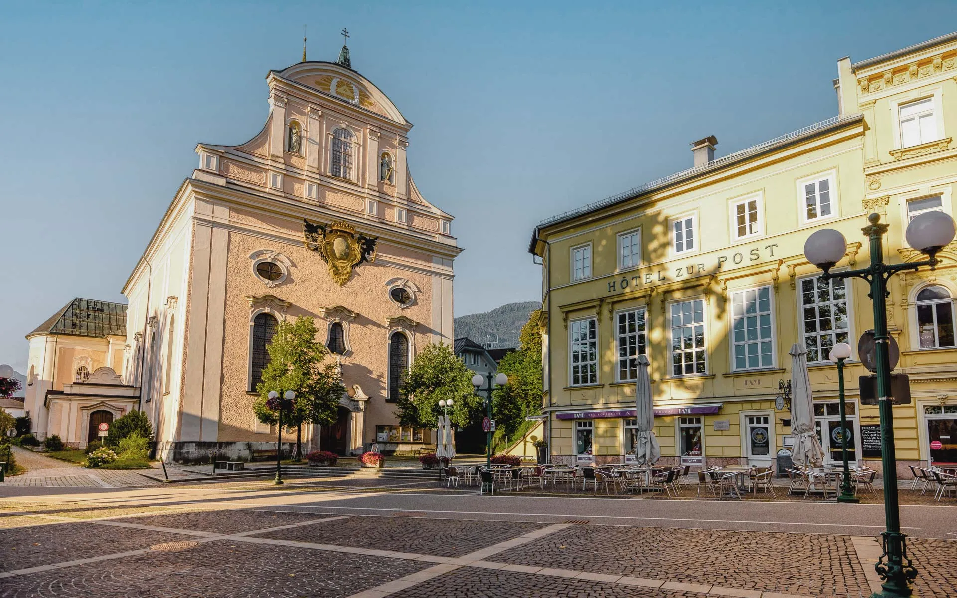 Sonnendurchfluteter Marktplatz in Bad Ischl, wo Sehenswürdigkeiten erstrahlen und vor dem Gebäude Sitzgelegenheiten stehen