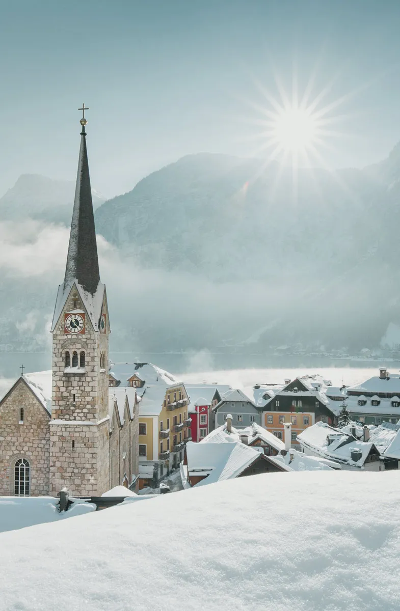 Winteraufnahme von Hallstatt im österreichischen Salzkammergut mit Kirchturm und bunten Hausfassaden