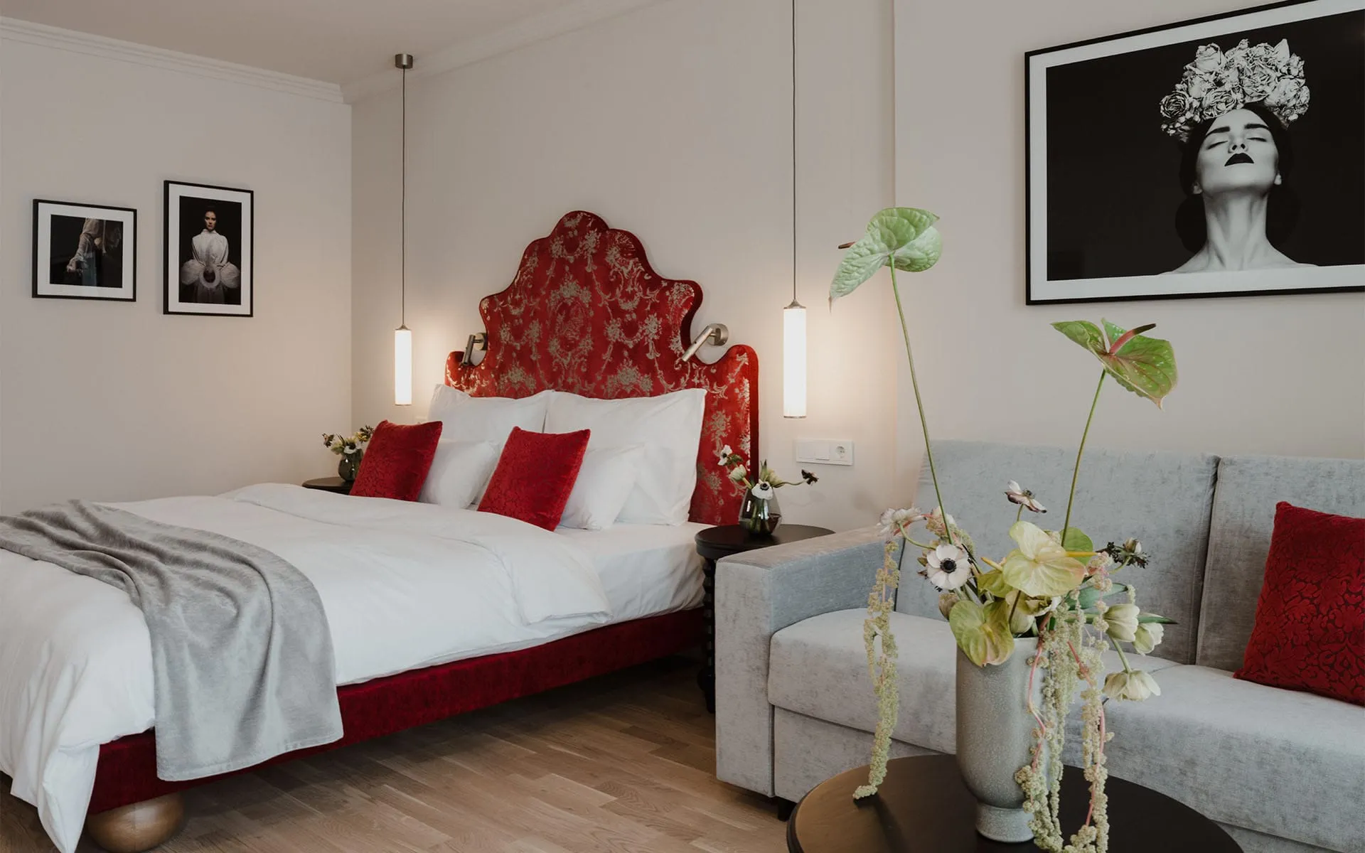 Luxuriöses Doppelzimmer im Grand Elisabeth in Bad Ischl mit rotem Samtbett, frischen Blumen und moderner Kunst an der Wand.