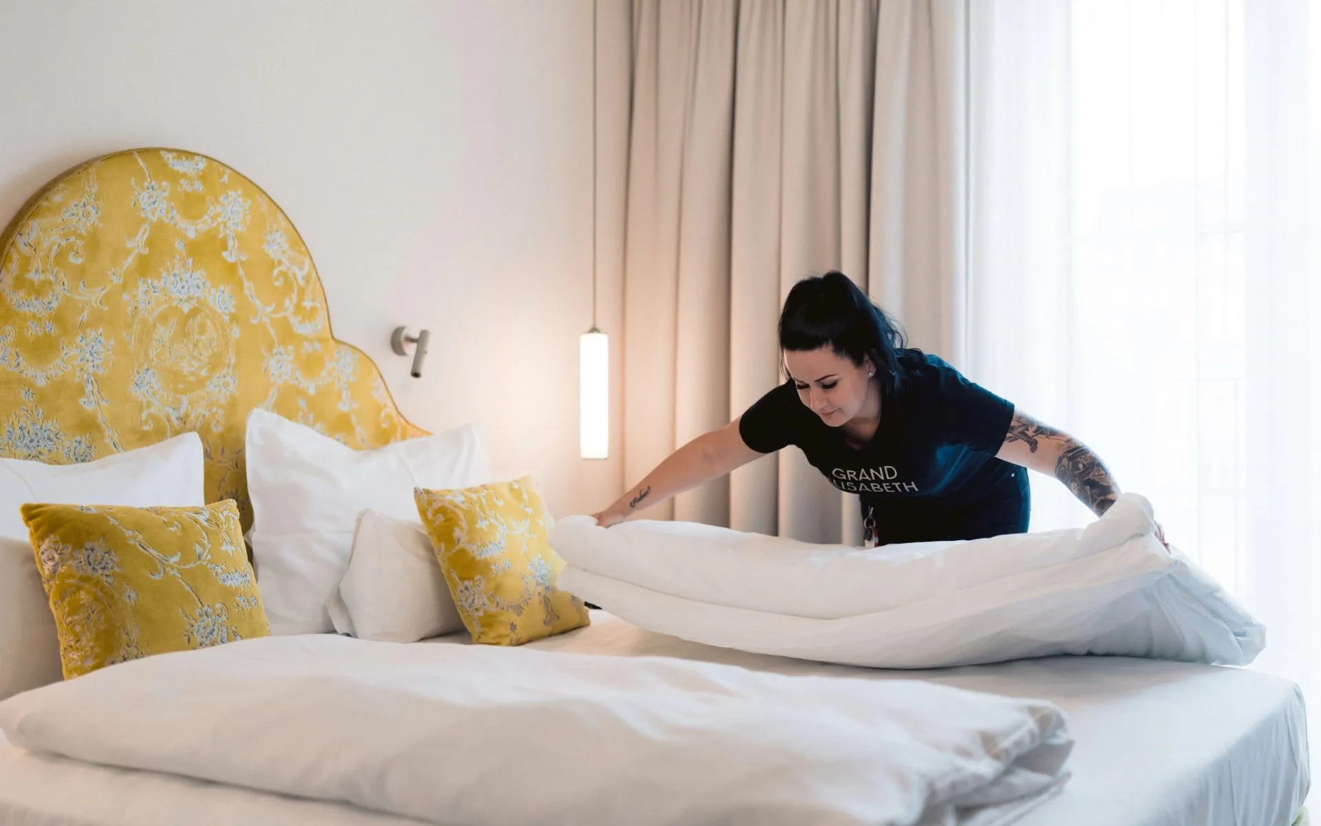 Eine Angestellte im Grand Elisabeth deckt für neuen Schlaf im Hotelzimmer des Grand Elisabeth ein