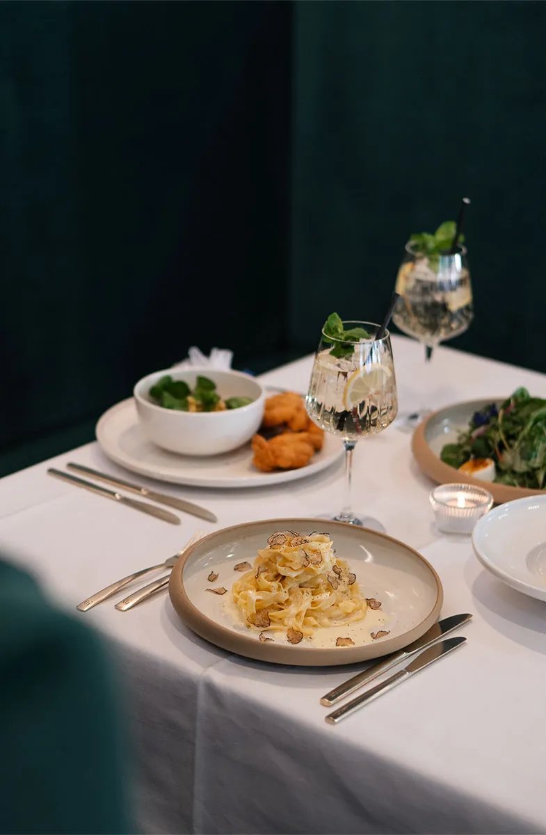 Abendessen im Grand Liberté mit Pasta, Salat und Getränken auf weiß gedecktem Tisch