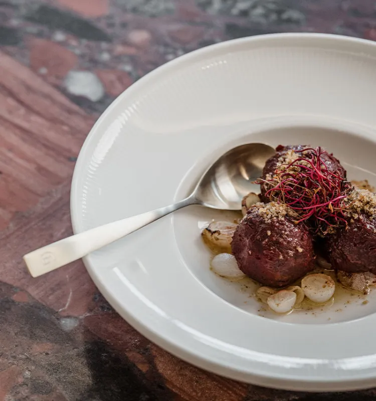 Kulinarische Spezialität im Grande Liberté auf dunklem Teller mit Röstzwiebeln und feiner Garnitur