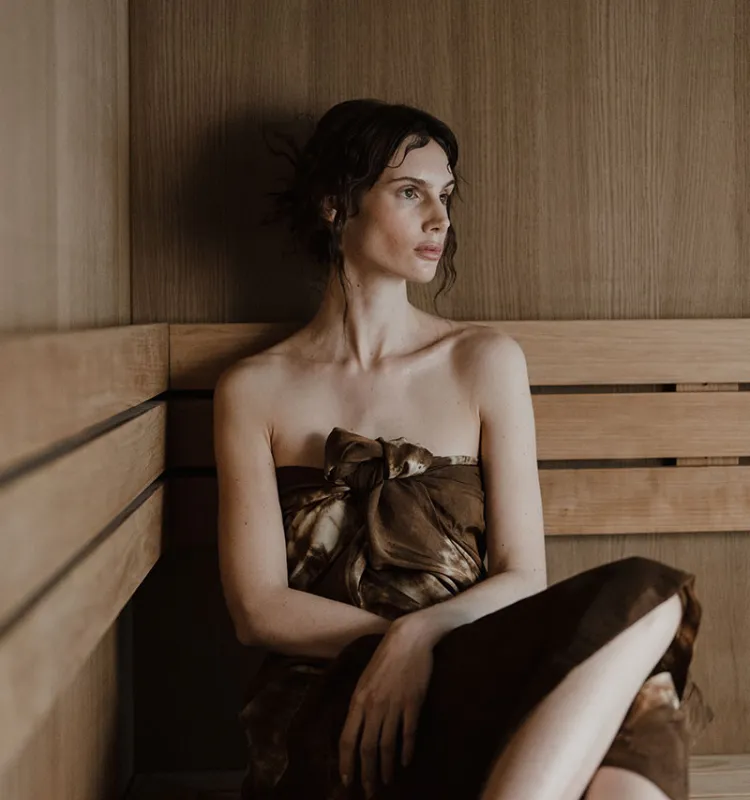 Frau entspannt in der Sauna des Grand Elisabeth, umgeben von warmem Holz und ruhiger Atmosphäre im Wellnessurlaub in Bad Ischl.