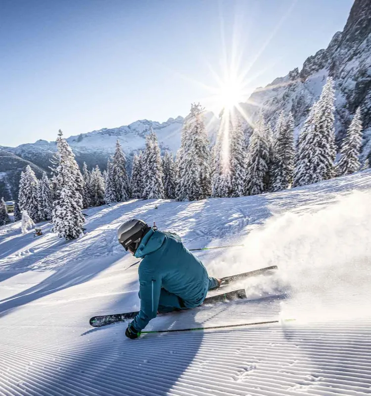 Eine Person fährt auf Skiern im Salzkammergut eine Piste hinab, im Hintergrund erheben sich majestätisch die Berge