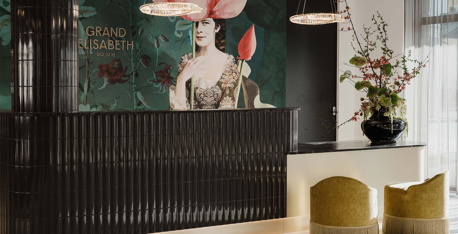 Rezeption des Grand Elisabeth Hotels in Bad Ischl mit Kunstwand, schwarzen Fliesen und Blumendekor.
