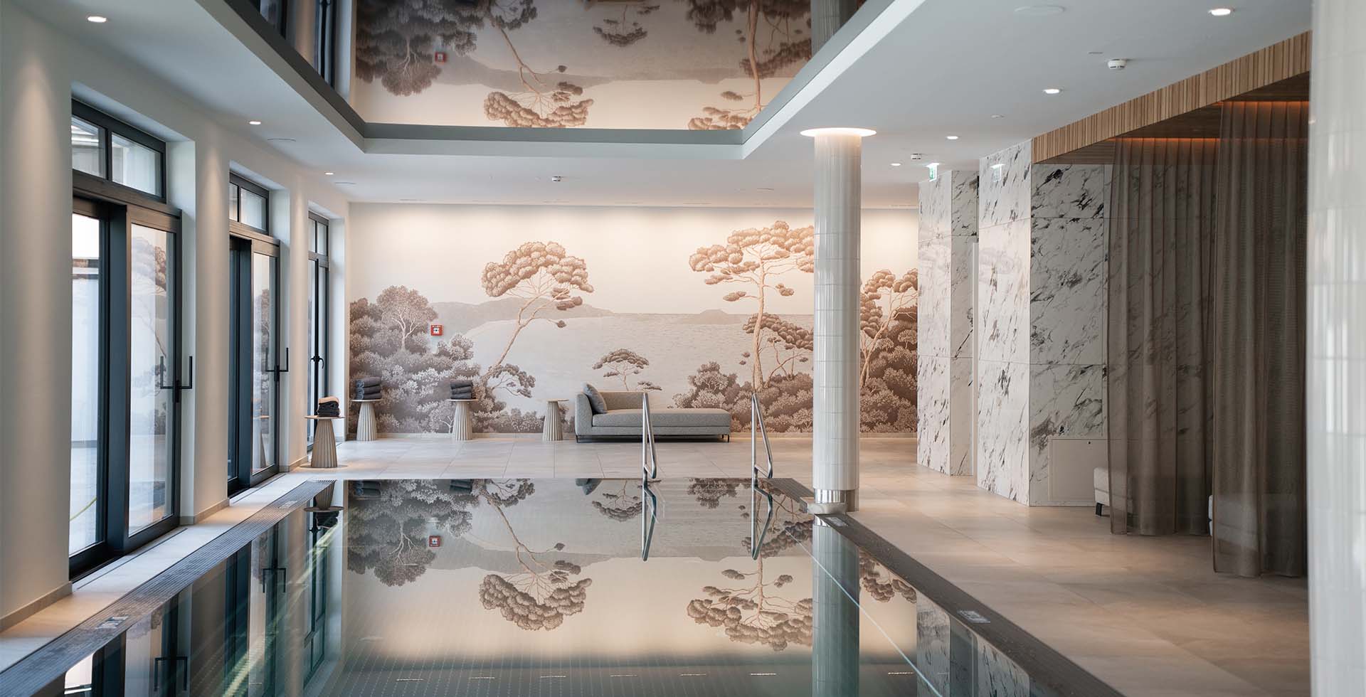 Innenpool im Wellnessbereich des Grand Elisabeth Hotels in Bad Ischl mit Marmorwänden, Wandmalerei und Sitzlounge.