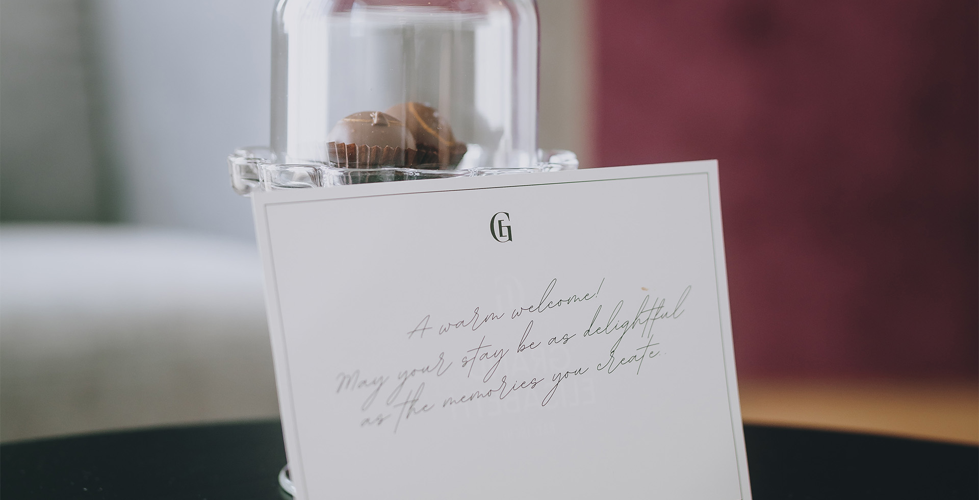 Begrüßungskarte mit handschriftlichem Willkommensgruß und feiner Praline in der Kaiser Suite des Grand Elisabeth Hotels.