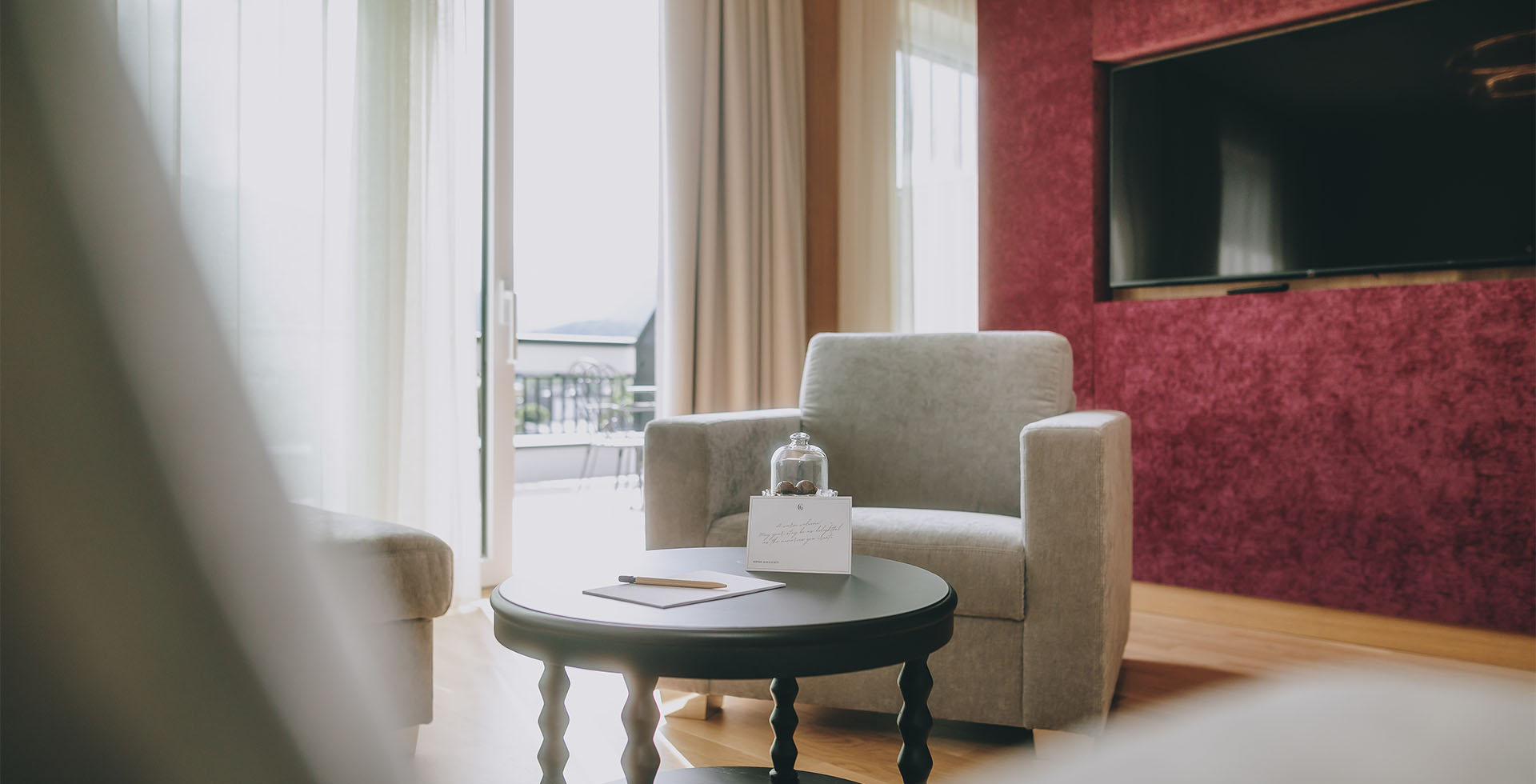 Moderner Lounge-Bereich in der Kaiser Suite des Grand Elisabeth mit Sesseln, Tisch und Blick auf den Balkon und über das Salzkammergut.