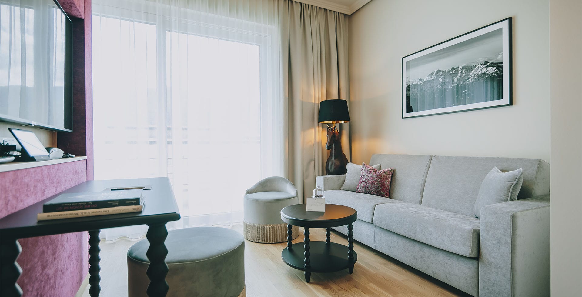 Heller Wohnbereich der Sisi Suite im Designhotel Grand Elisabeth mit Sofa, Couchtisch und Blick auf den Balkon im Salzkammergut.