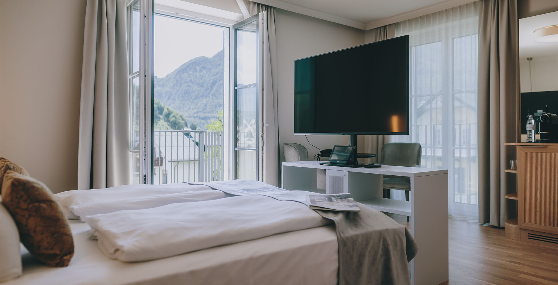 Blick vom Bett auf Fernseher und Balkon im Grand Elisabeth Hotel Bad Ischl