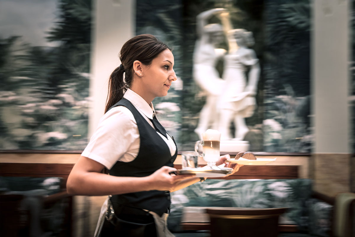 Kellnerin serviert Kaffee und Kuchen auf einem Tablett im klassischen Grand Café Restaurant Zauner Esplanade.