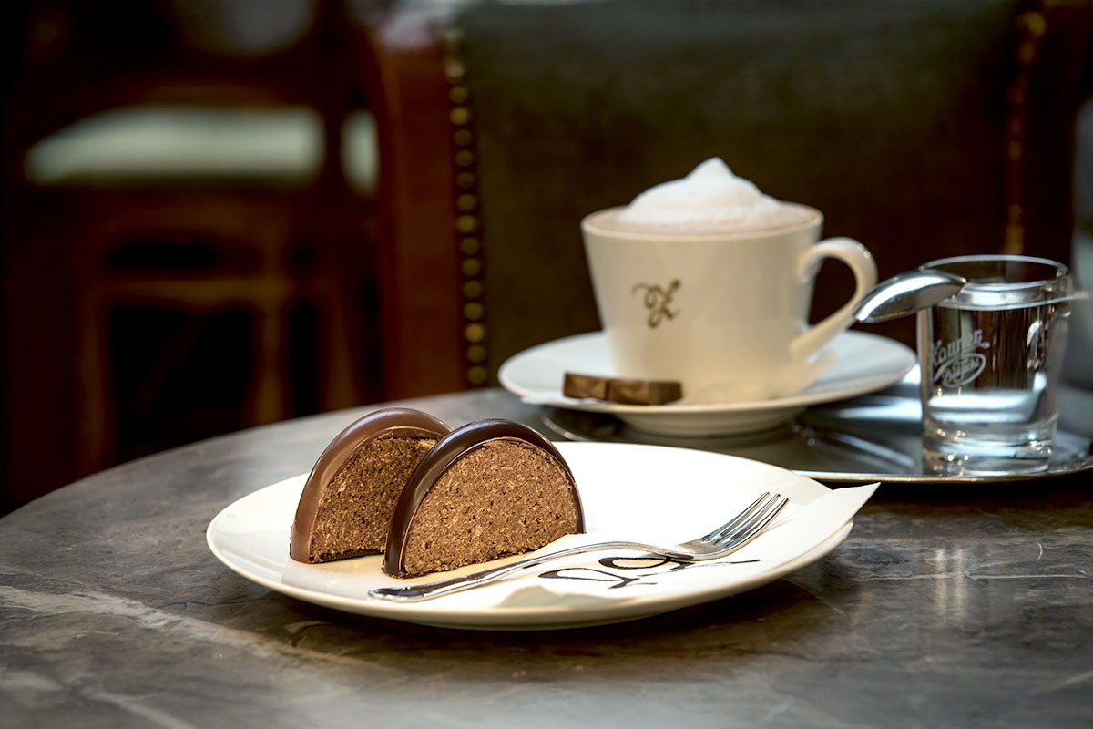 Teller mit Schokoladenstollen und Tasse Kaffee auf einem gedeckten Tisch im Grand Café Restaurant Zauner Esplanade