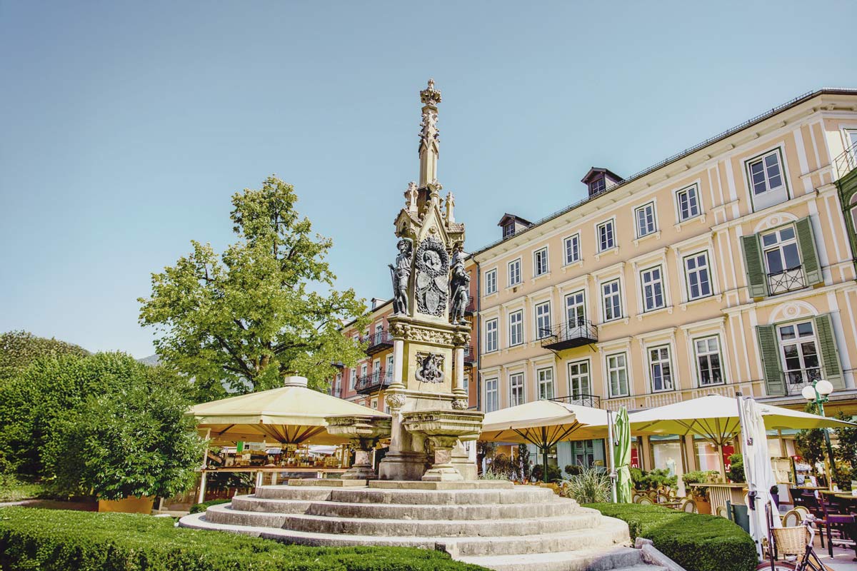 Statue als Sehenswürdigkeit im Kern der Altstadt von Bad Ischl an einem sonnigen Tag, umgeben von bunten Hausfassaden