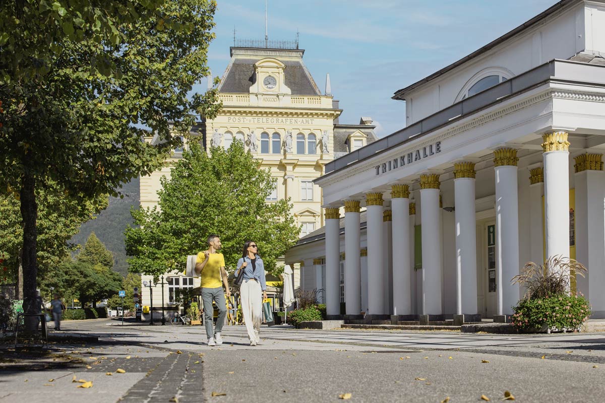 Ein Paar spaziert entlang der prunkvollen Trinkhalle in der Kulturhauptstadt Bad Ischl an einem sonnigen Tag