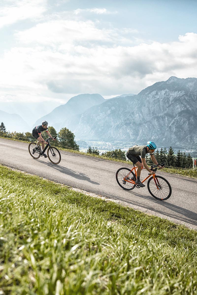 Zwei Radfahrer rollen bergab durchs Salzkammergut, vorbei am Traunsee und den Sehenswürdigkeiten rund um Bad Ischl