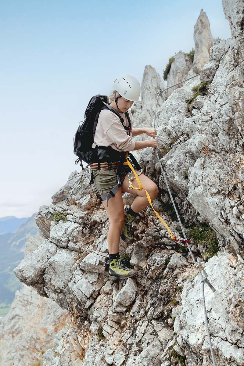 Am Klettersteig Katrin klettert eine Frau gesichert am Seil, im Hintergrund die malerische Region Bad Ischl