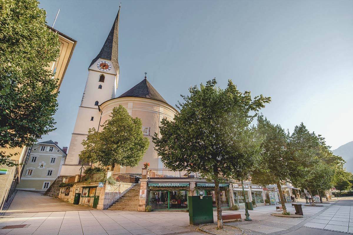 Bad Ischl im Sommer mit Kirchturm, Geschäften und Bäumen entlang der charmanten Gassen