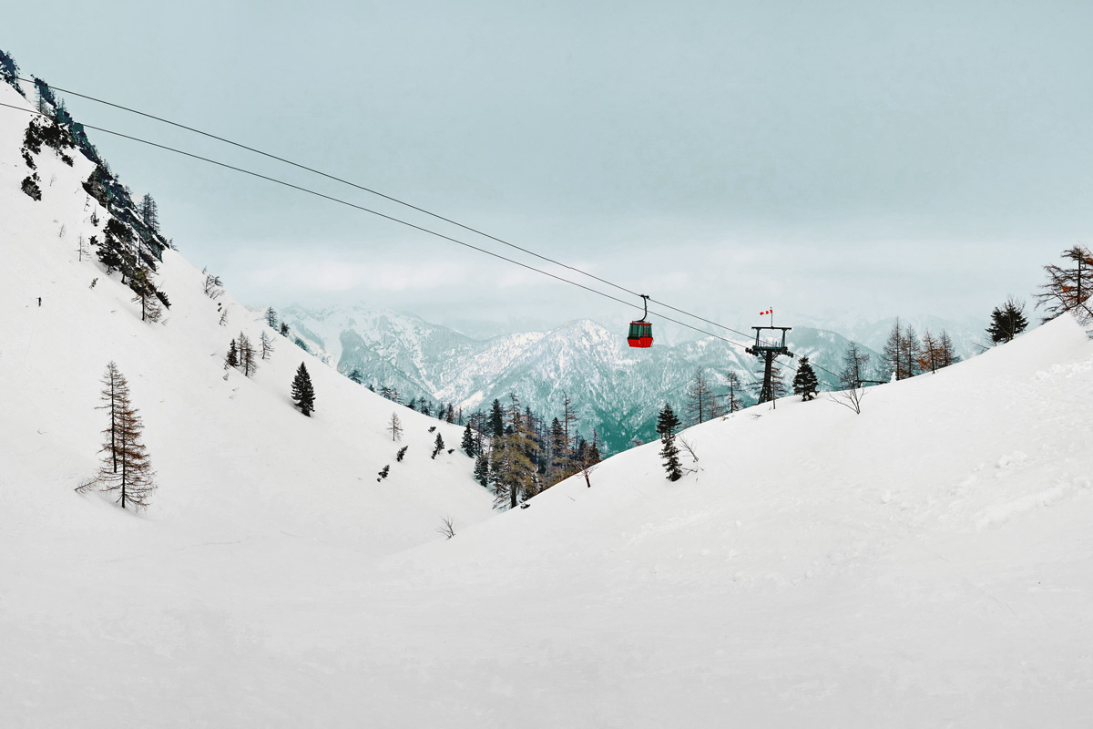 Eine Gondelbahn zieht durch die verschneite Berglandschaft des Salzkammerguts